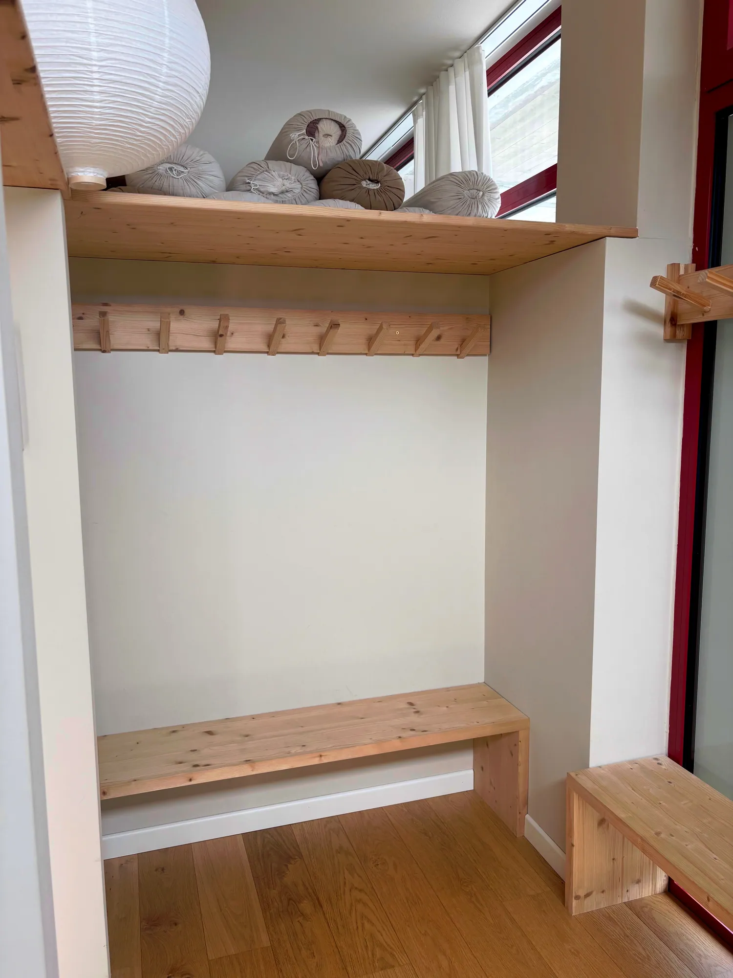 Angolo spogliatoio con panche di legno chiaro e bolster · Yoga Tribù